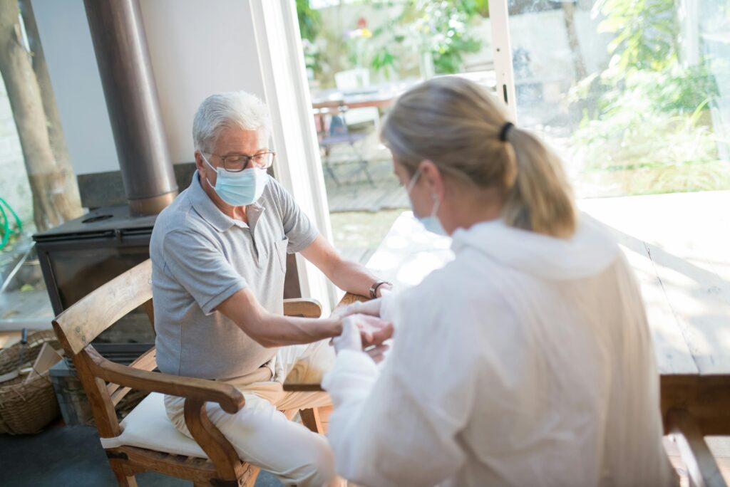 pexels-photo-8949833-8949833 A healthcare worker examining a senior man at home with face masks during the pandemic.
